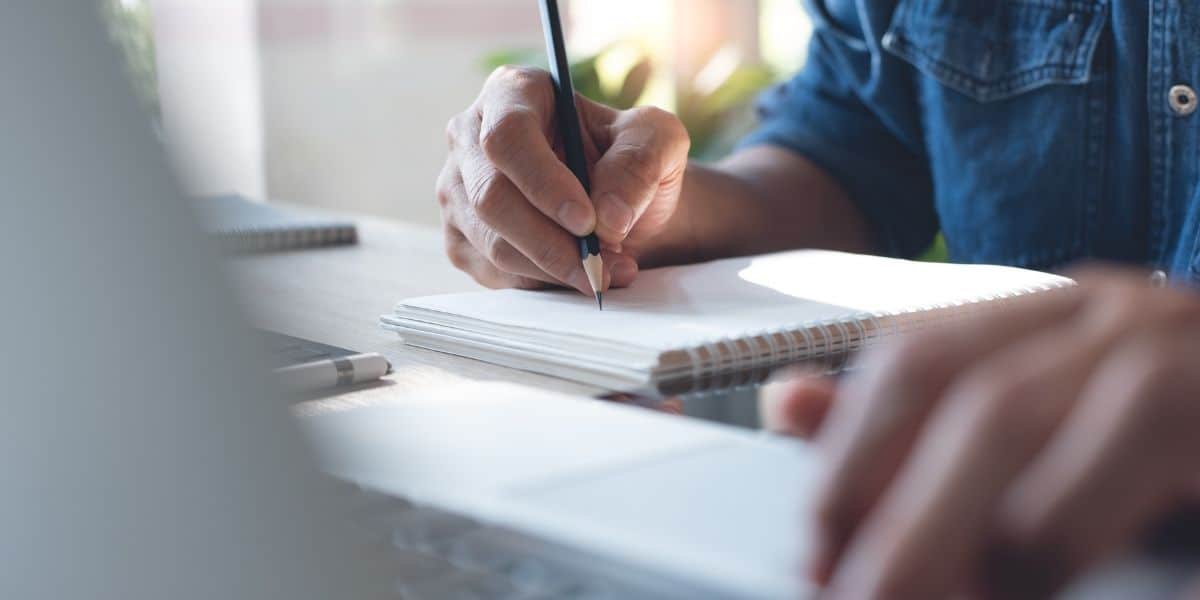 Efficient business planning and note-taking with a person writing in a notebook, symbolizing organization and productivity in a professional work environment.